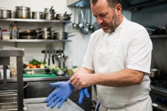 Chef professionnel en train de mettre des gants bleus dans une cuisine
